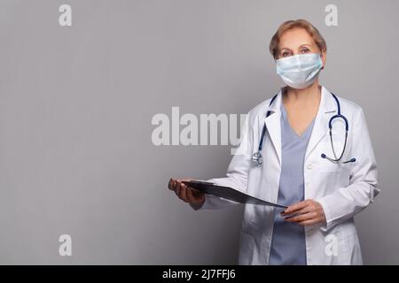 Médecin femme portant un manteau blanc avec stéthoscope dans le bureau de l'hôpital Banque D'Images