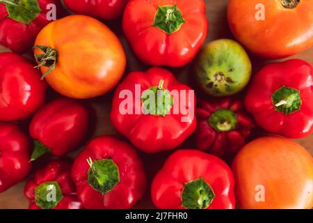 mini-poivrons et tomates fraîchement cueillis dans des tons rouges et orange vifs sur plateau en bois, concept de simples ingrédients naturels sains Banque D'Images