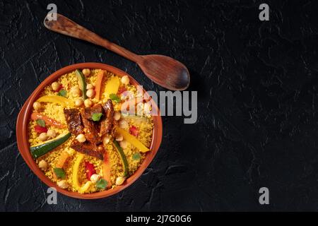 Couscous à la viande et aux légumes, dîner marocain festif, photo en hauteur avec un espace pour le texte sur fond noir Banque D'Images