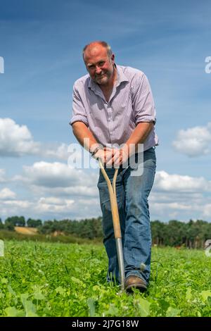 Le fermier se tenait dans son champ penché sur une bêche. Durham, Royaume-Uni. Banque D'Images