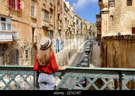 Fille voyageur sur un pont de fer à la recherche de bâtiments historiques dans le centre-ville de la Valette, Malte Banque D'Images