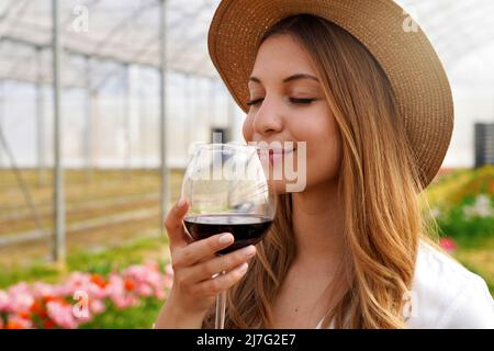 Gros plan de la belle femme qui sent le vin rouge du verre avec les yeux fermés Banque D'Images