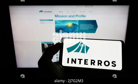 Personne tenant un smartphone avec le logo du conglomérat russe Interros sur l'écran devant le site Web. Mise au point sur l'affichage du téléphone. Banque D'Images