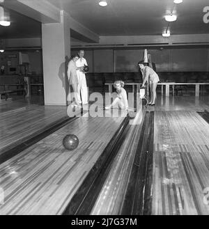 Bowling dans le 1950s. Un homme avec trois jeunes femmes dans une piste de bowling. Elles sont vêtues de jupes et de pulls à rayures courtes. Les trois filles sont toutes des actrices de théâtre : Ingrid Björk, UllaCarin Rydén et BRITA Ulfberg. Les spectacles Ewert Ekström les instruit dans le bowling. Il était joueur professionnel de bowling en 1930s et est actuellement instructeur et propriétaire du club de bowling. 1950. Suède Kristoffersson réf. AY35-7 Banque D'Images