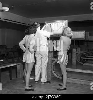 Bowling dans le 1950s. Un homme avec trois jeunes femmes dans une piste de bowling. Elles sont vêtues de jupes et de pulls à rayures courtes. Les trois filles sont toutes des actrices de théâtre : Ingrid Björk, UllaCarin Rydén et BRITA Ulfberg. Les spectacles Ewert Ekström les instruit dans le bowling. Il était joueur professionnel de bowling en 1930s et est actuellement instructeur et propriétaire du club de bowling. 1950. Suède Kristoffersson réf. AY36-8 Banque D'Images