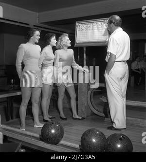 Bowling dans le 1950s. Un homme avec trois jeunes femmes dans une piste de bowling. Elles sont vêtues de jupes et de pulls à rayures courtes. Les trois filles sont toutes des actrices de théâtre : Ingrid Björk, UllaCarin Rydén et BRITA Ulfberg. Les spectacles Ewert Ekström les instruit dans le bowling. Il était joueur professionnel de bowling en 1930s et est actuellement instructeur et propriétaire du club de bowling. 1950. Suède Kristoffersson réf. AY37-5 Banque D'Images