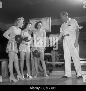 Bowling dans le 1950s. Un homme avec trois jeunes femmes dans une piste de bowling, ils sont vêtus de jupes et de pulls à rayures courtes. Les trois filles sont toutes des actrices de théâtre : Ingrid Björk, UllaCarin Rydén et BRITA Ulfberg. Les spectacles Ewert Ekström les instruit dans le bowling. Il était joueur professionnel de bowling en 1930s et est actuellement instructeur et propriétaire du club de bowling. 1950. Suède Kristoffersson réf. AY36-3 Banque D'Images