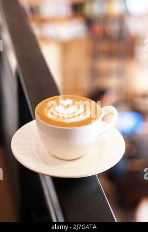 Une tasse de cappuccino au latte se dresse sur le fond du café en défocus. Tasse en céramique blanche et place pour le texte. Banque D'Images