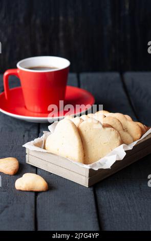 Tasse rouge et cœurs de biscuit sur fond noir Banque D'Images
