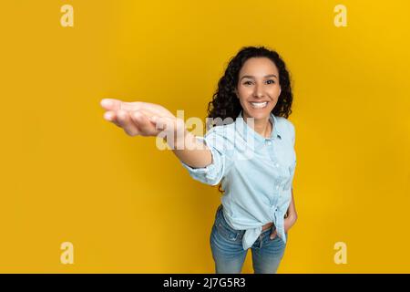 Une jeune femme souriante dépasse la main, essayant de tenir quelque chose Banque D'Images