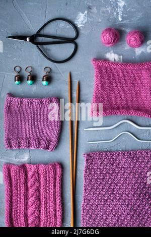 Vue de dessus: Les accessoires de tricotage et les échantillons de produits tricotés se trouvent sur un fond en béton gris. Lieu d'inscription. Banque D'Images