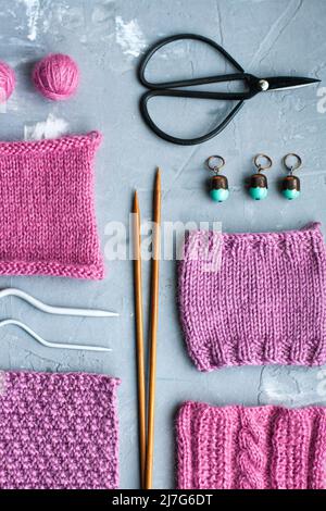 Vue de dessus: Les accessoires de tricotage et les échantillons de produits tricotés se trouvent sur un fond en béton gris. Lieu d'inscription. Banque D'Images