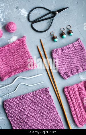 Vue de dessus: Les accessoires de tricotage et les échantillons de produits tricotés se trouvent sur un fond en béton gris. Lieu d'inscription. Banque D'Images
