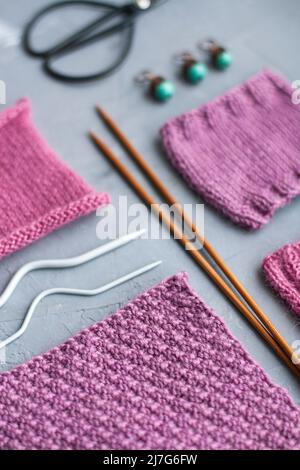 Vue de dessus: Les accessoires de tricotage et les échantillons de produits tricotés se trouvent sur un fond en béton gris. Lieu d'inscription. Banque D'Images
