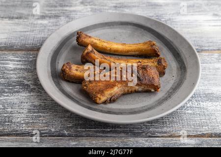 côtes de porc sur une assiette en bois sur fond de bois gris. Vue latérale, gros plan. Banque D'Images