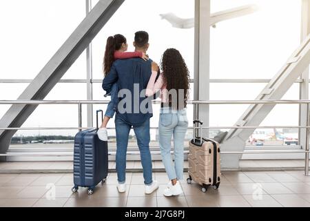 Famille de trois personnes à l'aéroport avec vue de la fenêtre au départ de l'avion Banque D'Images