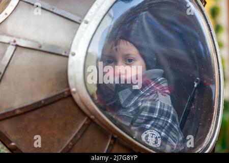 Jeune garçon regardant vers vous par la fenêtre d'une attraction de carrousel. Bruxelles Banque D'Images