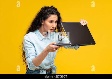 Une jeune femme effrayée utilise un ordinateur portable en studio Banque D'Images