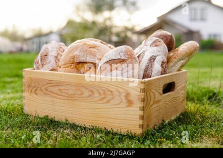 Panier en bois plein de pain frais au coucher du soleil. Boulangerie maison. Banque D'Images