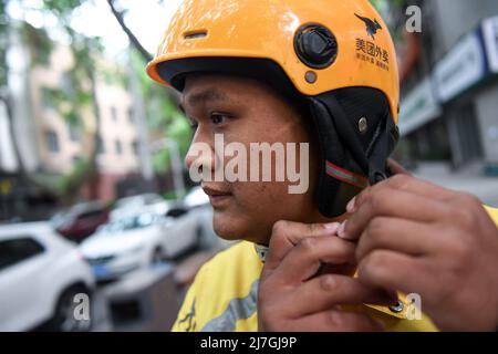 (220509) -- ZHENGZHOU, 9 mai 2022 (Xinhua) -- le livreur Hua Qilong boucle son casque à Zhengzhou, province du Henan au centre de la Chine, 8 mai 2022. Avec ses collègues, Hua Qilong, un livreur de 25 ans à Zhengzhou, travaille en première ligne de la prévention et du contrôle des épidémies et livre de la nourriture, des médicaments et d'autres nécessités quotidiennes pour garantir les moyens de subsistance des gens. « En général, je livre d'abord des médicaments et des commandes à partir des hôpitaux, ce qui est urgent pour les clients », a déclaré M. Hua. A partir de mai 4, à l'exception des zones de gestion fermées, d'autres zones du centre-ville de Zhengzhou ont été Banque D'Images