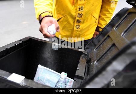 (220509) -- ZHENGZHOU, 9 mai 2022 (Xinhua) -- le livreur Hua Qilong désinfecte sa boîte à colis à Zhengzhou, dans la province du Henan en Chine centrale, le 8 mai 2022. Avec ses collègues, Hua Qilong, un livreur de 25 ans à Zhengzhou, travaille en première ligne de la prévention et du contrôle des épidémies et livre de la nourriture, des médicaments et d'autres nécessités quotidiennes pour garantir les moyens de subsistance des gens. « En général, je livre d'abord des médicaments et des commandes à partir des hôpitaux, ce qui est urgent pour les clients », a déclaré M. Hua. À partir de mai 4, à l'exception des zones de gestion fermées, d'autres zones du centre-ville de Zhengzhou HAV Banque D'Images