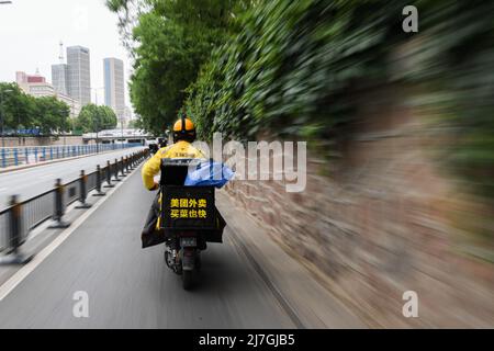 (220509) -- ZHENGZHOU, le 9 mai 2022 (Xinhua) -- le livreur Hua Qilong livre des colis à Zhengzhou, province du Henan en Chine centrale, le 8 mai 2022. Avec ses collègues, Hua Qilong, un livreur de 25 ans à Zhengzhou, travaille en première ligne de la prévention et du contrôle des épidémies et livre de la nourriture, des médicaments et d'autres nécessités quotidiennes pour garantir les moyens de subsistance des gens. « En général, je livre d'abord des médicaments et des commandes à partir des hôpitaux, ce qui est urgent pour les clients », a déclaré M. Hua. À partir de mai 4, à l'exception des zones de gestion fermées, d'autres zones du centre-ville de Zhengzhou ont été pl Banque D'Images