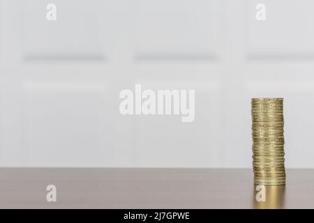 Livre britannique Sterling GBP pile de pièces de couleur or, image laissée sur une surface en bois avec un mur lambrissé blanc pour un espace de copie plus propre Banque D'Images