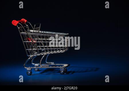 Mini panier chariot de supermarché panier à trolley (vide) gros plan sur un fond bleu Banque D'Images