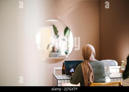 Jeune femme indépendante utilisant un ordinateur portable tout en travaillant à domicile Banque D'Images