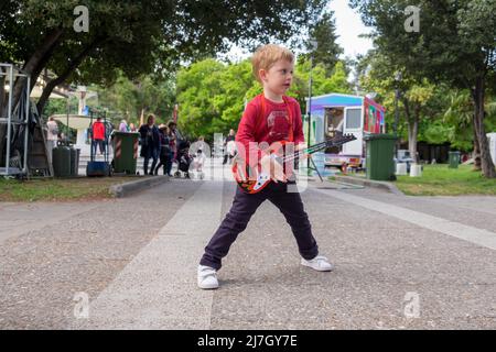 Mignon petit garçon drôle jouant son jouet de guitare dans un festival Banque D'Images