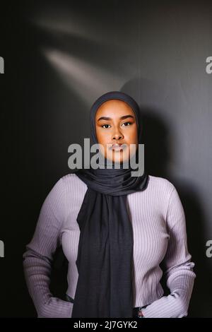 Jeune femme debout sur fond gris Banque D'Images