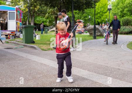 Mignon petit garçon drôle jouant son jouet de guitare dans un festival Banque D'Images