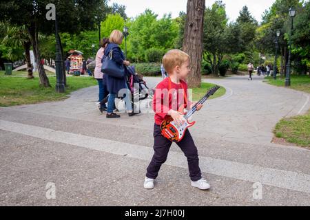 Mignon petit garçon drôle jouant son jouet de guitare dans un festival Banque D'Images