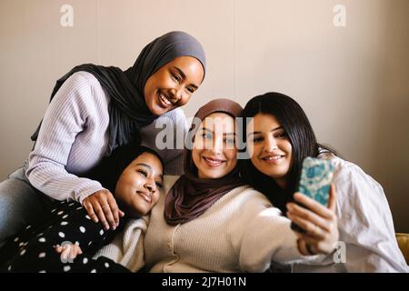 Jeune femme souriante emportant un selfie avec des amis grâce à un smartphone à la maison Banque D'Images