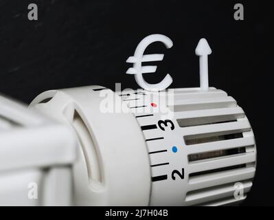 un gros plan d'un thermostat de radiateur avec un signe de l'euro et une flèche vers le haut symbolisent la hausse des coûts de chauffage, concept de la hausse des prix de l'énergie à l'avenir Banque D'Images