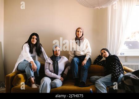 Portrait de jeunes femmes assises ensemble sur un canapé dans le salon à la maison Banque D'Images