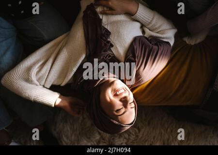 Jeune femme souriante, les yeux fermés, couchée par des amis sur un canapé à la maison Banque D'Images