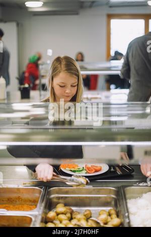 Une fille prend de la nourriture au bar pendant la pause déjeuner à la cafétéria Banque D'Images