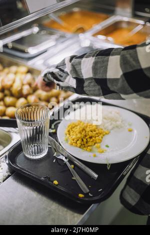 Garçon remplissant les aliments dans l'assiette du bar à nourriture pendant la pause déjeuner Banque D'Images