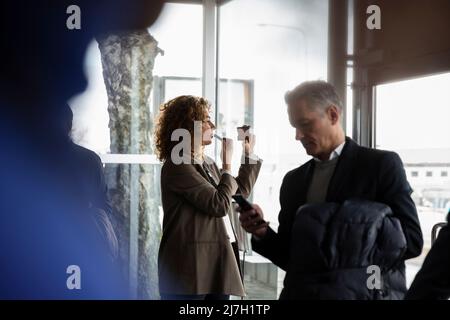 Vue latérale d'une femme d'affaires appliquant un rouge à lèvres avant le séminaire au centre de conférence Banque D'Images
