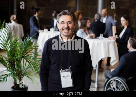 Homme d'affaires souriant portant une carte d'identité dans le centre de conférence Banque D'Images