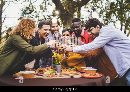 Compagnie d'amis joyeux ayant plaisir à toasting pic nic dans la campagne de ferme - concept de style de vie avec les amis heureux multigénérationnels jusqu'à Banque D'Images