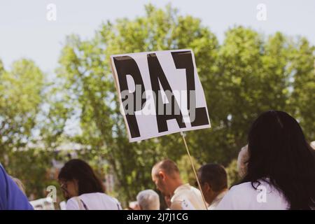 Les gens au rassemblement pour la paix. Femme tenant une affiche avec le texte PAIX ou PAZ en espagnol dans sa main contre les arbres verts. Une manifestation un rassemblement de Banque D'Images