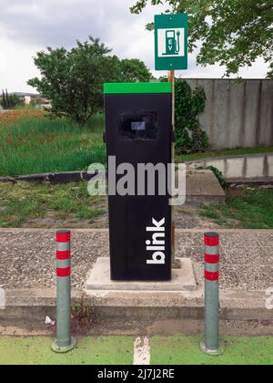 Station électrique pour voiture électrique EV avec logo clignotant. Point de charge utilisé pour fournir de l'énergie renouvelable à bas prix aux véhicules, contre le terrain de coquelicots sur le parking ouvert à Thessalonique, Grèce. Banque D'Images