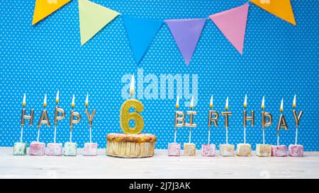 Joyeux anniversaire à partir de lettres aux chandelles sur un fond bleu avec un espace de copie à pois blanc. Gâteau d'anniversaire joyeux avec bougie dorée Banque D'Images