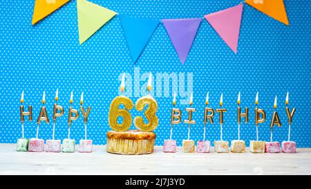 Joyeux anniversaire à partir de lettres aux chandelles sur un fond bleu avec un espace de copie à pois blanc. Gâteau d'anniversaire joyeux avec bougie dorée Banque D'Images