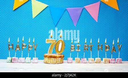 Joyeux anniversaire à partir de lettres aux chandelles sur un fond bleu avec un espace de copie à pois blanc. Gâteau d'anniversaire joyeux avec bougie dorée Banque D'Images