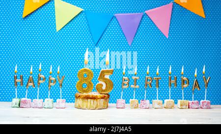 Joyeux anniversaire à partir de lettres aux chandelles sur un fond bleu avec un espace de copie à pois blanc. Gâteau d'anniversaire joyeux avec bougie dorée Banque D'Images