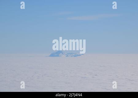 Vue de dessus du sommet d'une montagne enneigée qui s'élève des nuages. Pictyre pris par un vol. Banque D'Images