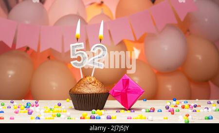 Ballons décorations et une bougie d'anniversaire heureuse avec un nombre dans un gâteau. Joyeux anniversaire voeux en couleurs roses pour une fille, espace copie. Muffin Banque D'Images